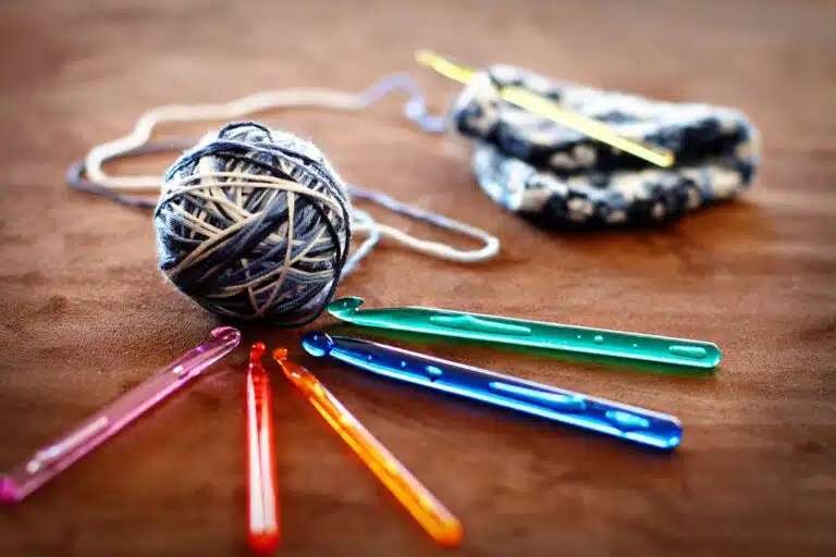bola de linha de crochê com diversos ganchos coloridos.