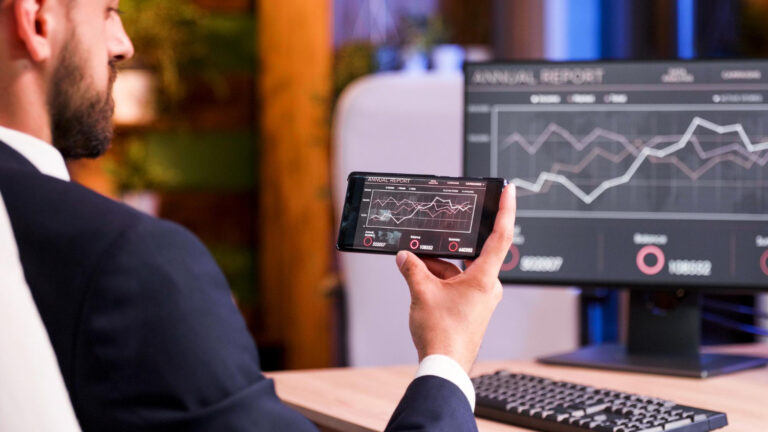 Homem visualizando plataforma de trading mobile e no computador