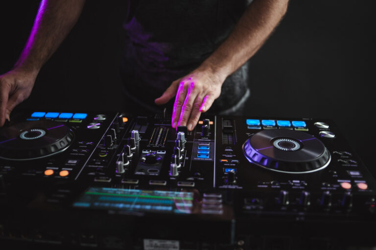 Mãos de um DJ operando uma mesa de mixagem.